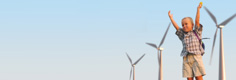Image:  Boy standing in front of three wind turbines